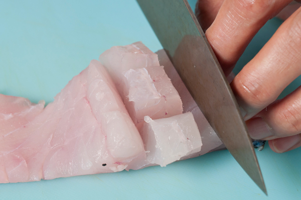 スズキは、身のほうから包丁の刃を入れ、そのまま皮の近くまで切り込み、約1,5cm間隔に縦横の切り目を入れて、塩、酒を振りかける。