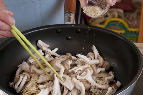 フライパンの真ん中に鮭を並べてショウガを散らす。周りにシメジを入れてシメジの上に昆布茶を振りかけ、全体に酒を振ってフタをして中火にかける。