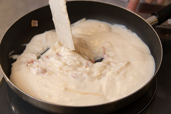 短冊切りにしたベーコン、薄切りにした玉ねぎをいためる。火が通ったらホワイトソース、牛乳、にんにくを入れ混ぜる。