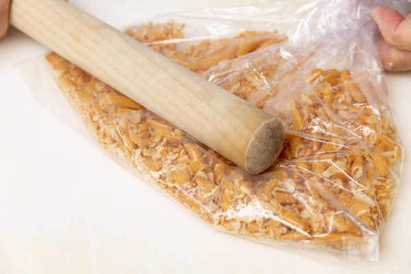 ビニール袋に柿の種をいれて、麺棒などで細かくたたく。