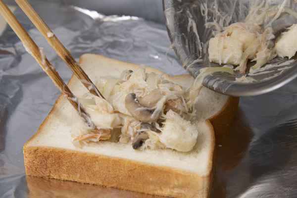 中心部を四角に切った食パンをアルミホイルにのせる。切ったパンは①と混ぜ、食パンの中に流しいれる。