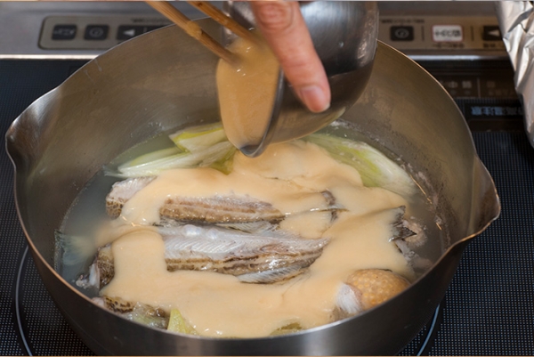 はたはたが煮えたら白味噌を入れて、少し煮詰めたら出来上がり。ゆでて4cmくらいに切った春菊と皮を千切りにした柚子を添え、お好みで七味をかける。