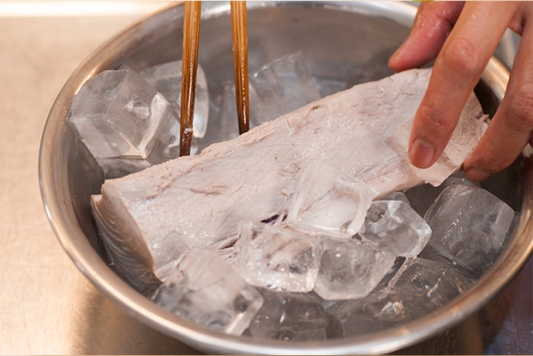 沸騰したお湯にカツオを数秒くぐらせる。表面の色が変わったらすぐ氷水に漬ける。