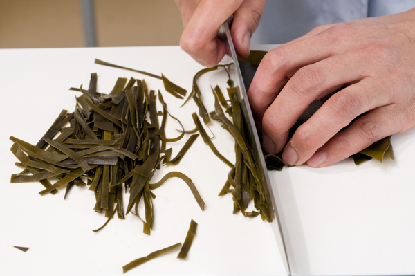 昆布は水でもどしてから、細く切る。糸こんにゃくは下茹でをして、4cmほどに切る。豚バラ薄切り肉、かまぼこ、にんじんはそれぞれ短冊に切る。