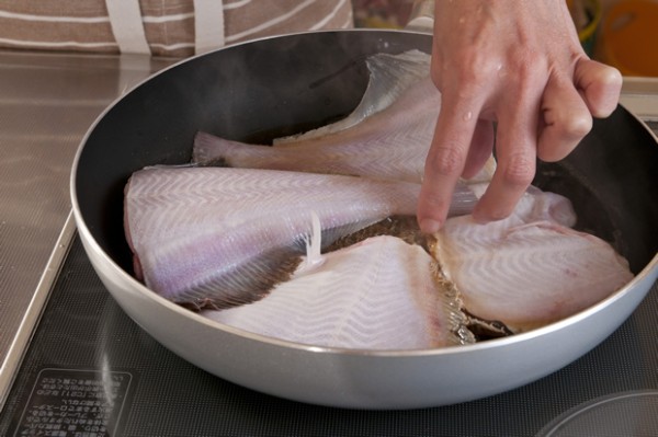 フライパンで水と酒を沸騰させ、塩昆布を加えてひと混ぜしたら昆布茶で味を整えカレイを並べ入れる。