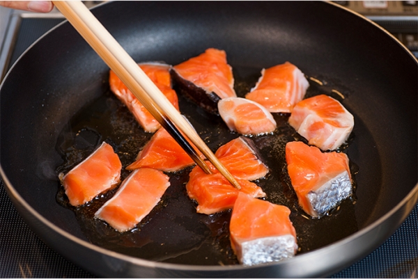 フライパンにゴマ油を熱して、一口大にした塩鮭を炒める。