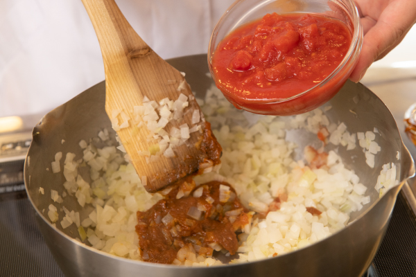 ショウガ、玉ねぎをバターでいため、飴色になったら水、トマト缶とあわせて煮立たせ、スープカレーの素（またはスパイスなど）を入れる。